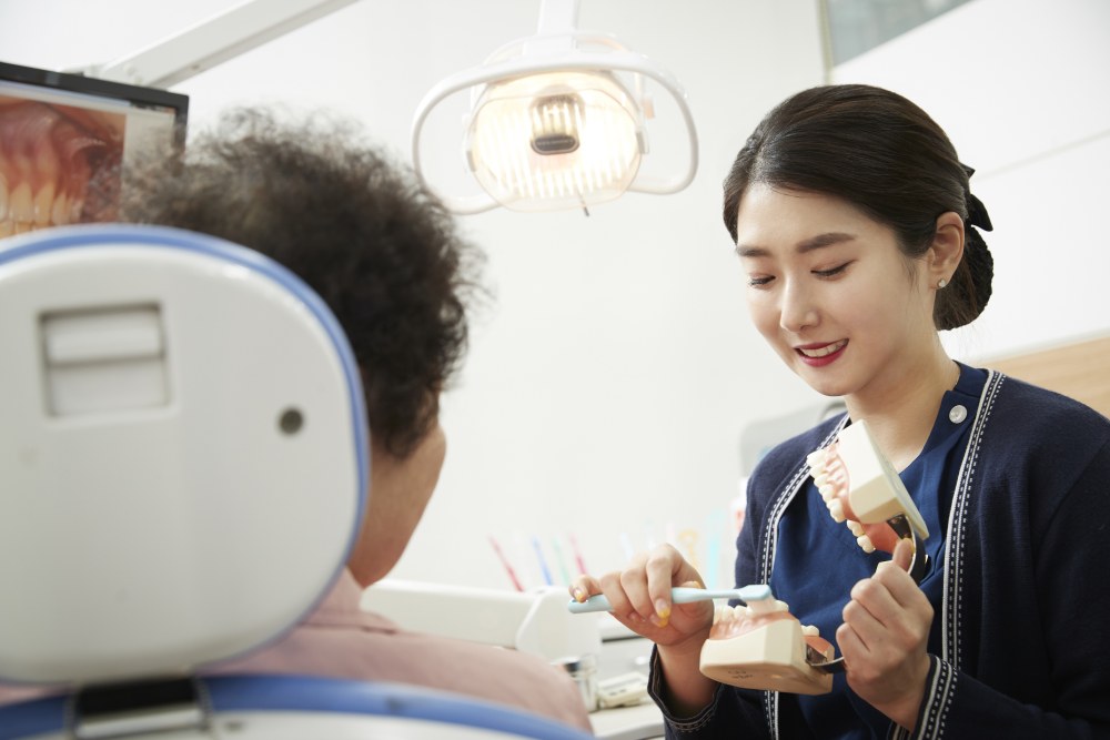 치과위생사가 환자에게 올바른 양치질 방법(TBI)과 구강용품 사용법을 교육하고 있다