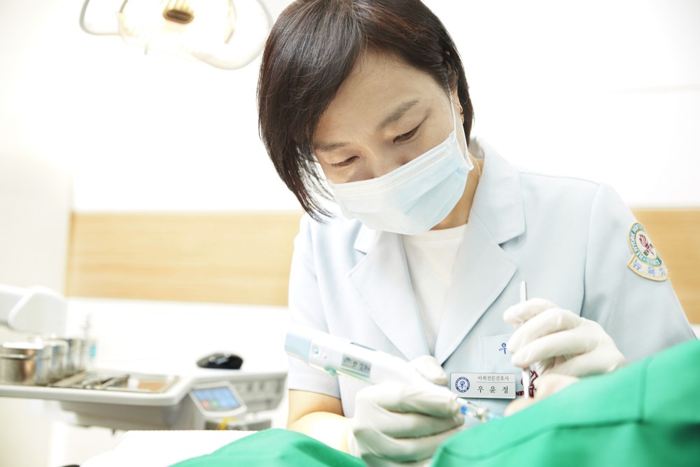 뉴욕치과 마취 담당 인력이 치과 체어에 누운 환자에게 마취를 진행하고 있는 모습