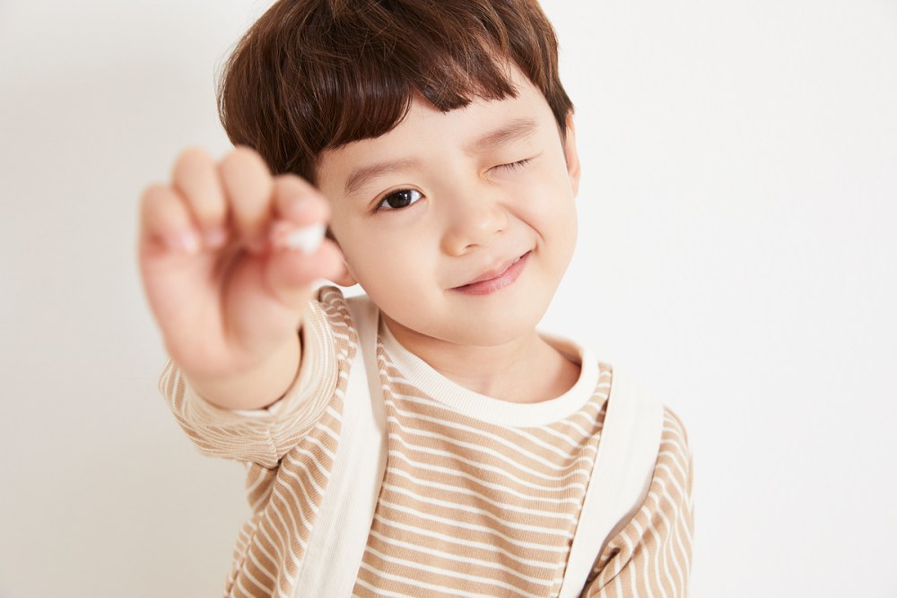 빠진 유치를 들고 윙크하는 어린이