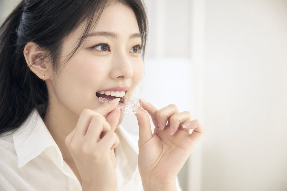 투명 교정 장치를 손으로 끼우는 20대 여성 (AI 생성 이미지)